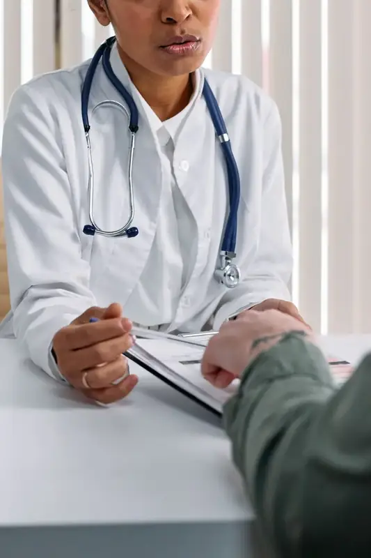 A doctor talking with an adult patient across a consulting desk