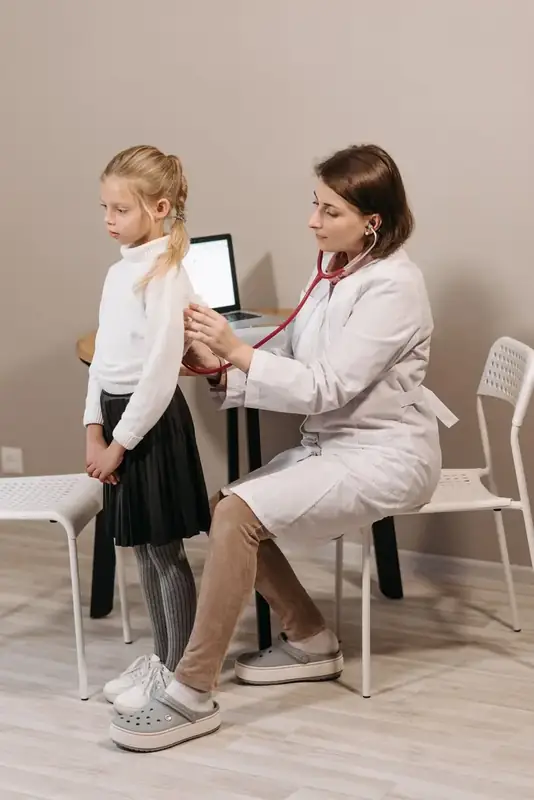 A paediatrician examining a young girl with a stethoscope